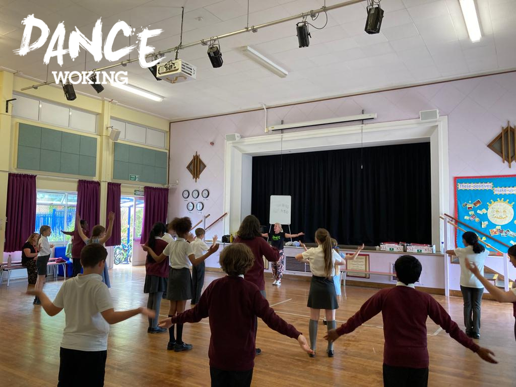 Children standing facing the teacher with arms out in a school gym